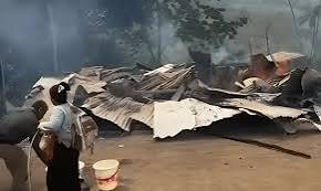 Damaged structures and debris in a village affected by conflict.
