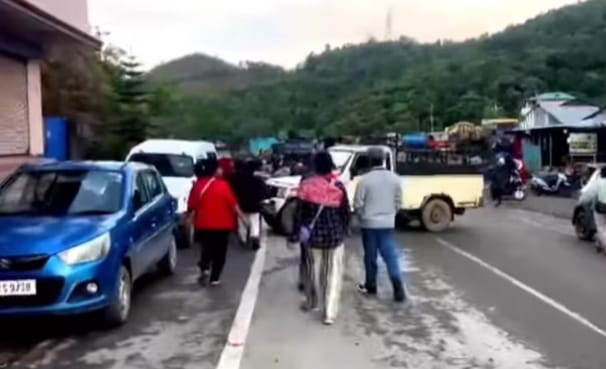 Residents gather on a road in Moreh amid tensions following the arrest of a village volunteer.
