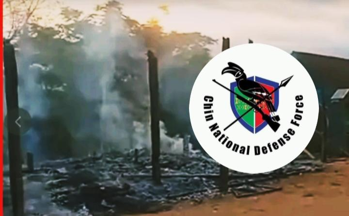Burnt village structures with Chin National Defense Force emblem overlay
